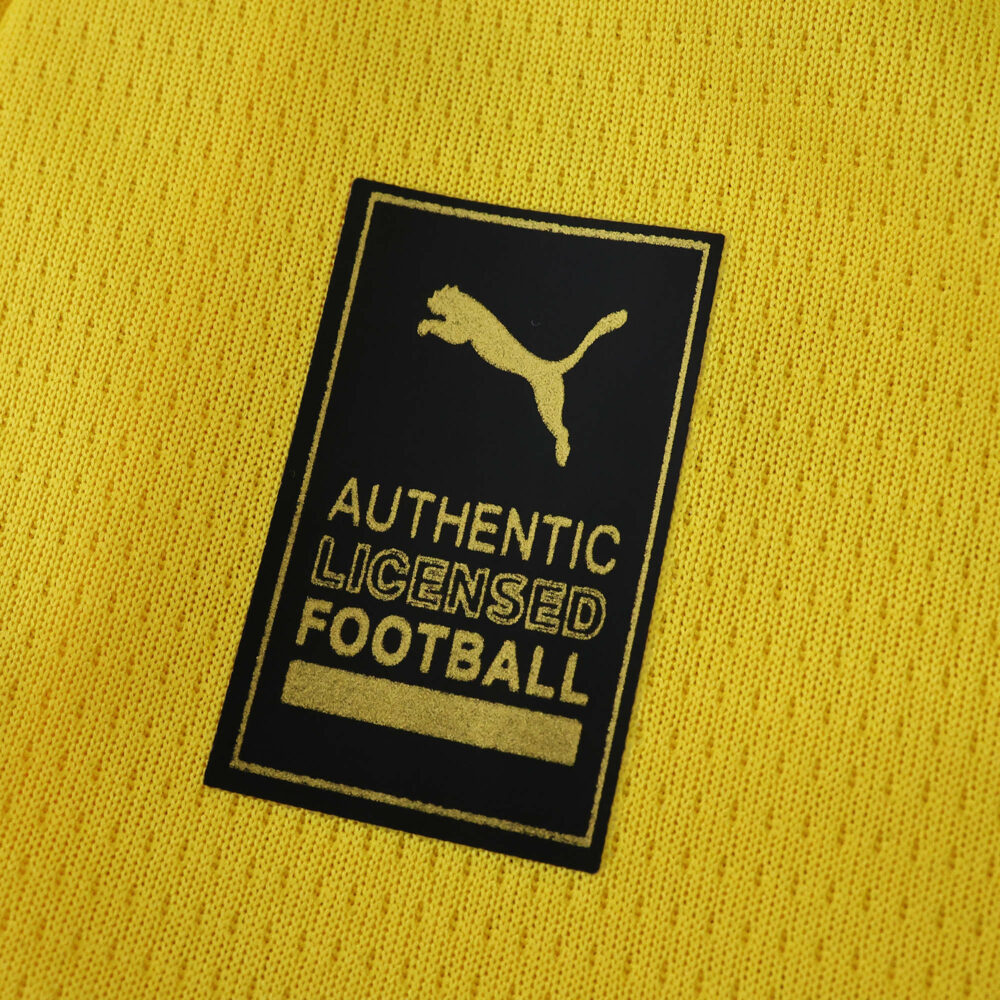 Close-up of the yellow Borussia Dortmund 2025/26 home fan jersey with Puma authentic licensed football badge.