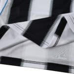 Close-up of Newcastle United 2025/26 home fan jersey fabric showing black and white stripes.