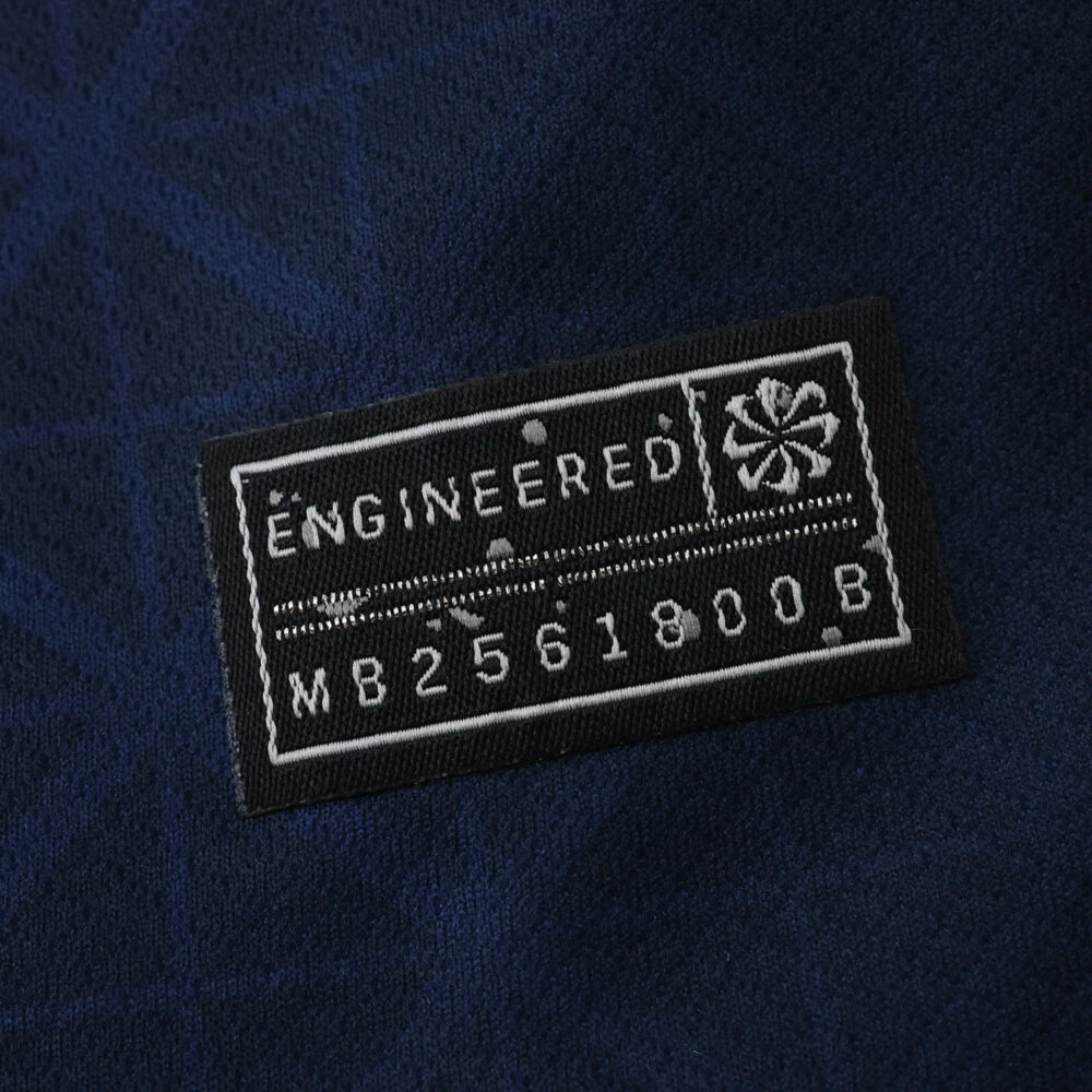 Close-up of the official engineering patch on the Paris Saint-Germain 2025/26 home fan jersey.