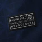 Close-up of the official engineering patch on the Paris Saint-Germain 2025/26 home fan jersey.