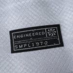 Close-up of the "Engineered SMPL 1972" tag on the VfL Wolfsburg Away 2025/26 Fan Version jersey.