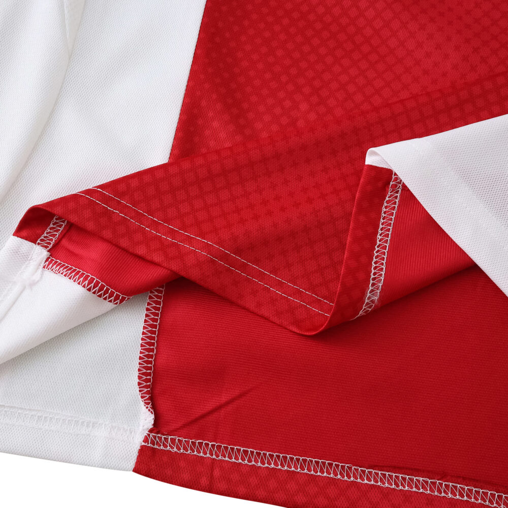 Close-up of the Ajax Home 2025/26 Fan Version jersey fabric showing red and white stitching detail.