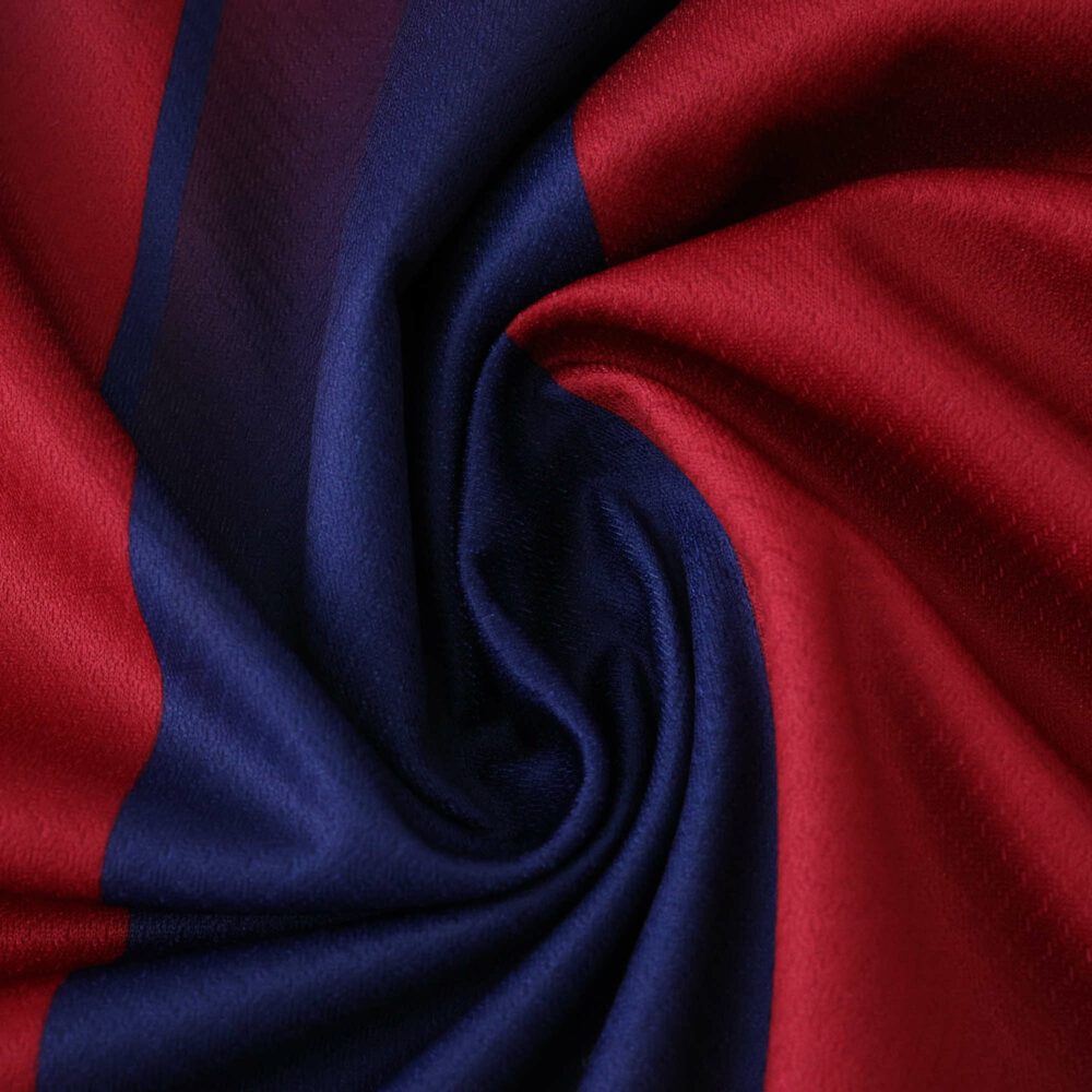 Close-up of Barcelona 2025/26 home fan jersey fabric, showing red and blue colors.