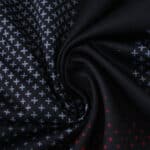 Close-up of Bayer Leverkusen 2025/26 home fan jersey fabric with white and red cross patterns on black.