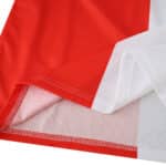 Close-up of Feyenoord 2025/26 home fan jersey fabric, showing red and white color blocks and stitching.