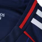 Detail view of the Olympique Lyonnais Away 2025/26 Fan Version jersey, featuring red and white stripes on navy fabric.