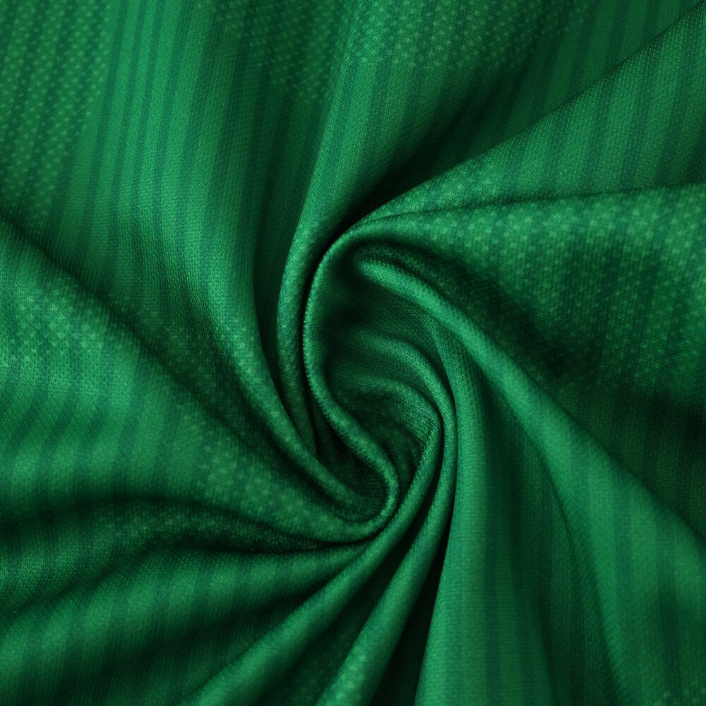 Close-up of Real Betis 2025/26 home fan jersey fabric showing green color and subtle textured pattern.