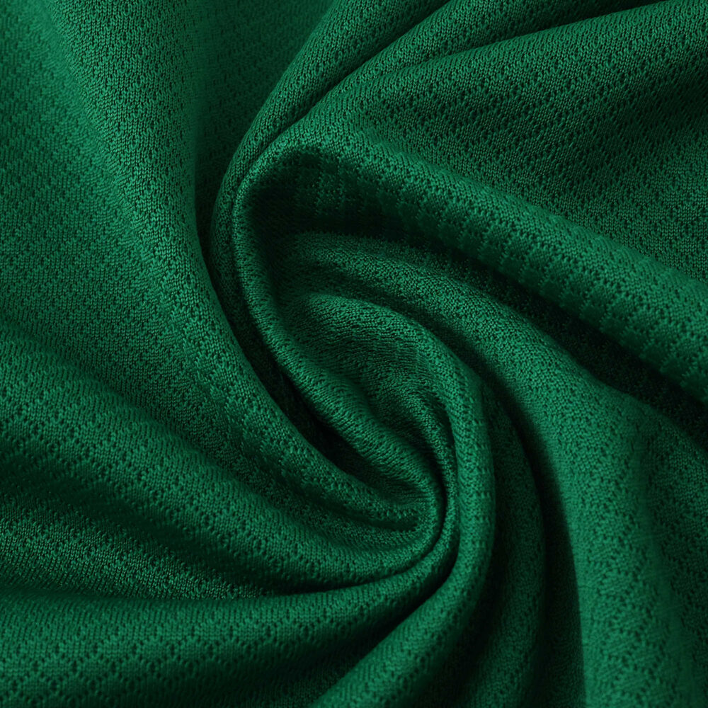 Close-up of VfL Wolfsburg 2025/26 Home Fan Version jersey fabric, showing green textured material.