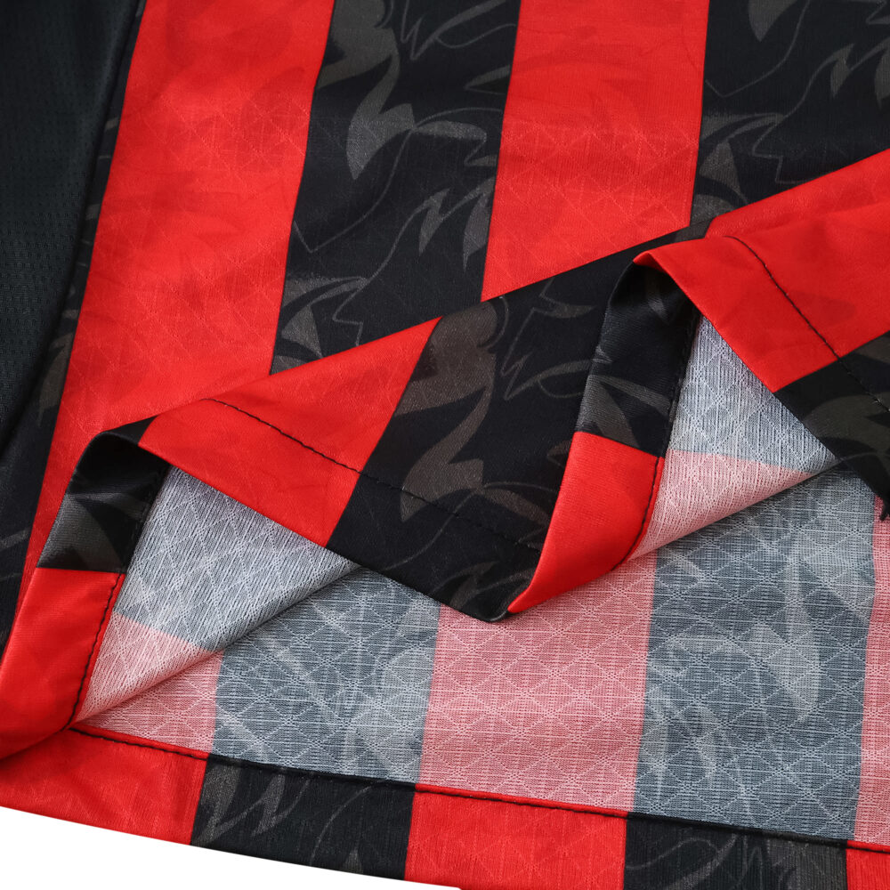 Close-up of AC Milan 2025/26 Home Player Version jersey fabric showing red and black stripes with textured details.