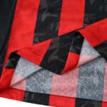 Close-up of AC Milan 2025/26 Home Player Version jersey fabric showing red and black stripes with textured details.