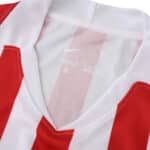Close-up of the Atlético Madrid 2025/26 home fan jersey featuring red and white stripes and a white collar.
