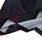 Close-up of Bayer Leverkusen 2025/26 home fan jersey fabric showing red and white cross patterns on black.