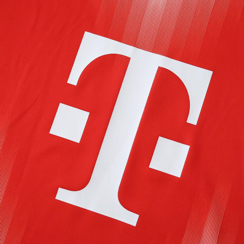 Close-up of the Telekom logo on the red Bayern Munich Home 2025/26 Fan Version jersey.
