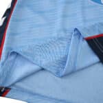 Close-up of Celta Vigo 2025/26 home fan jersey fabric, showing stitching and light blue material.