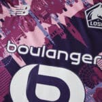 Close-up of Lille LOSC 2025/26 away fan jersey featuring sponsor logos and cityscape pattern in pink and purple.