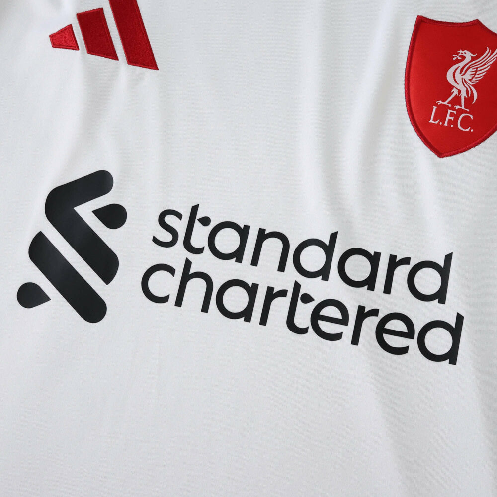 Close-up of Liverpool Away 2025/26 Fan Version jersey, showing club crest and sponsor logo on white fabric.