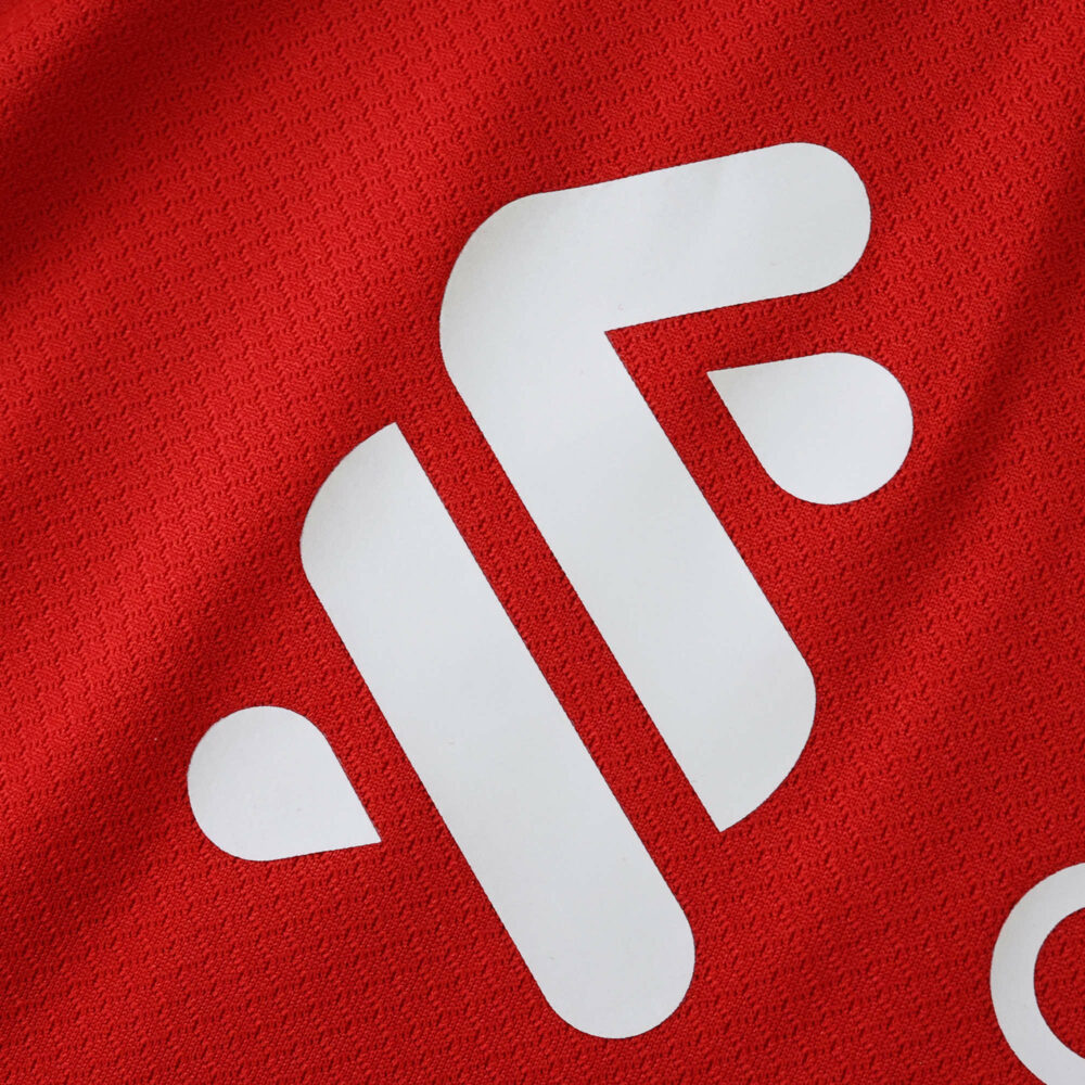 Close-up of the Liverpool Home 2025/26 Fan Version jersey showing a white sponsor logo on red fabric.