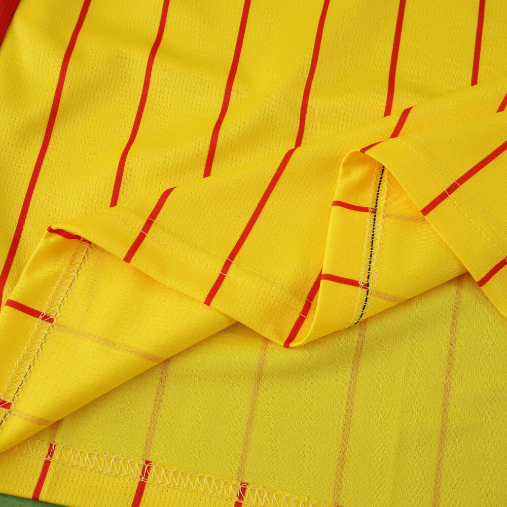 Close-up of RC Lens 2025/26 home fan jersey fabric, featuring yellow material with red vertical stripes.