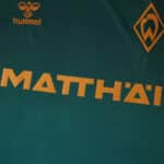 Close-up of Werder Bremen Third 2025/26 Fan Version jersey with sponsor and club logos in gold.