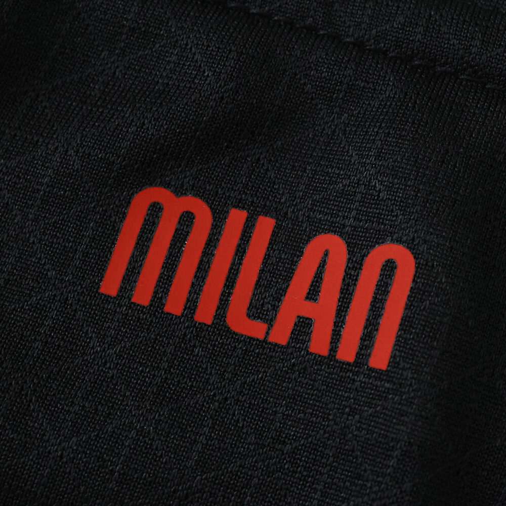 Close-up of the red "MILAN" text on the AC Milan Home 2025/26 Player Version jersey fabric.