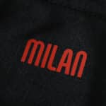 Close-up of the red "MILAN" text on the AC Milan Home 2025/26 Player Version jersey fabric.