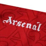 Close-up of the Arsenal 2025/26 Home Player Version jersey with "Arsenal" in white gothic script on red fabric.