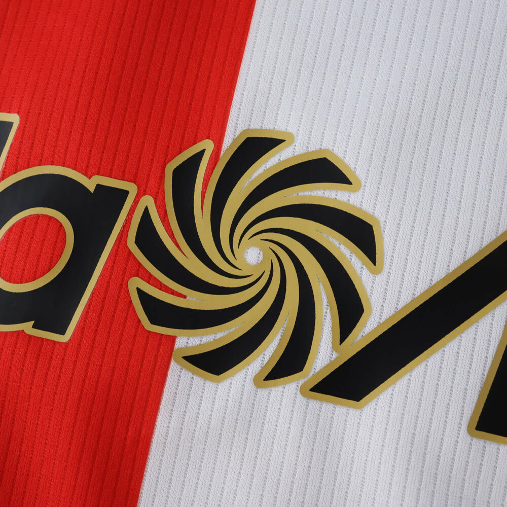 Close-up of Feyenoord Home 2025/26 Fan Version jersey, showing sponsor logo detail on red and white fabric.
