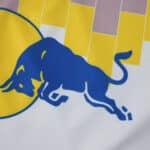 Close-up of the Leeds United 2025/26 home fan jersey featuring a blue bull and yellow geometric pattern.