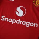 Close-up of Manchester United 2025/26 home jersey showing Snapdragon sponsor and club crest.