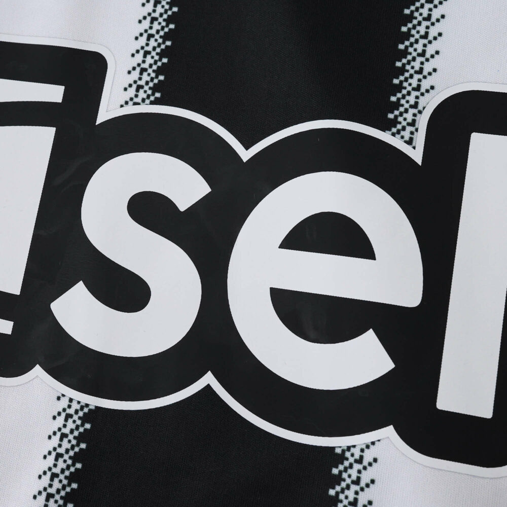 Close-up of Newcastle United 2025/26 home fan jersey showing part of the sponsor logo on black and white stripes.