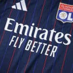 Close-up of Olympique Lyonnais 2025/26 away fan jersey with club crest and Emirates Fly Better sponsor logo.