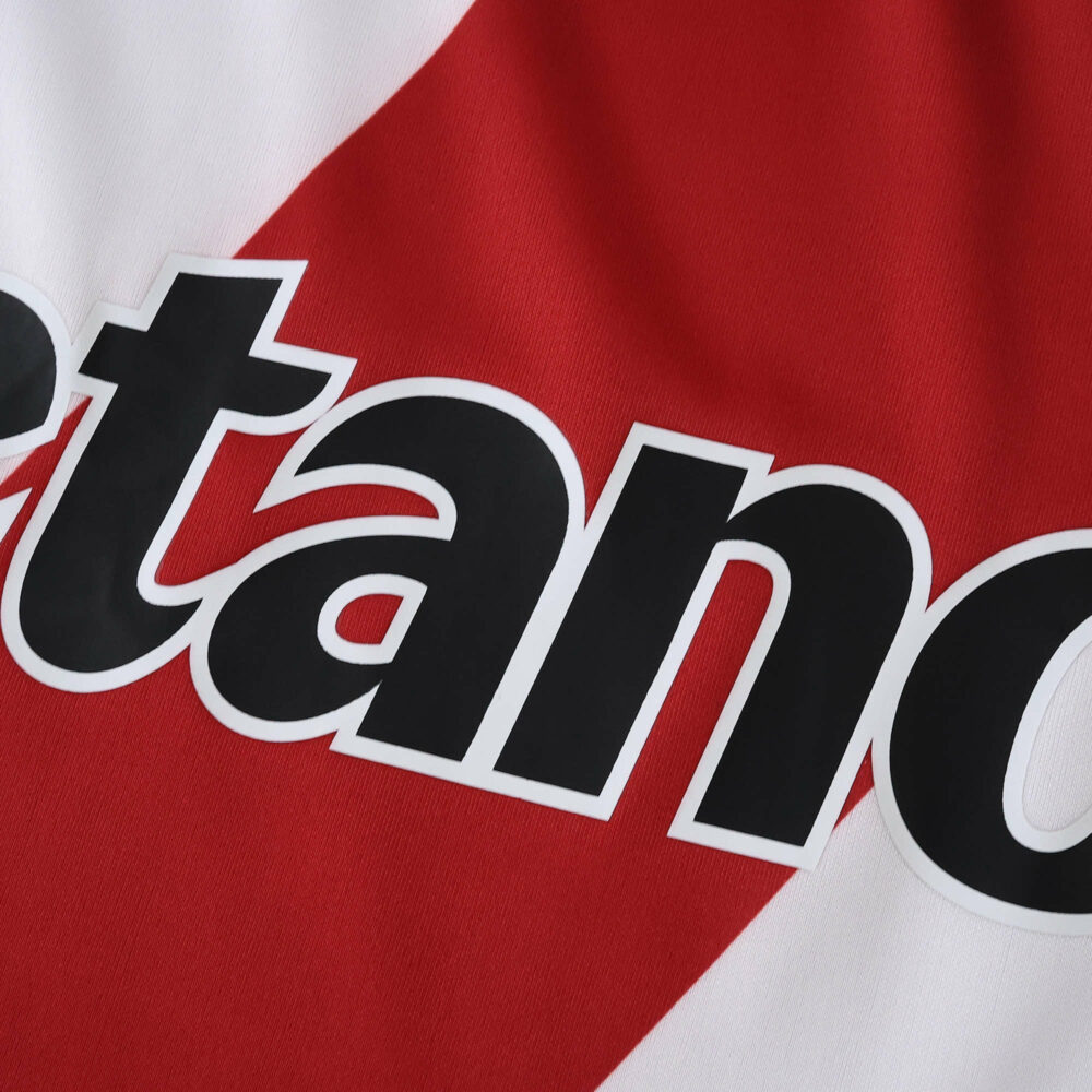 Close-up of River Plate Home 2025/26 Fan Version jersey showing sponsor text on red and white diagonal stripe.