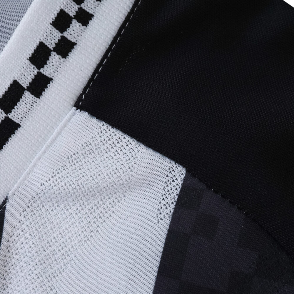Close-up of the Santos FC Away 2025/26 Fan Version jersey fabric showing black and white checkered pattern.