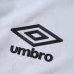 Close-up of the black Umbro logo on the white Santos FC 2025/26 Home Player Version jersey fabric.