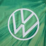 Close-up of the VfL Wolfsburg 2025/26 home fan jersey featuring a white VW logo on green fabric.