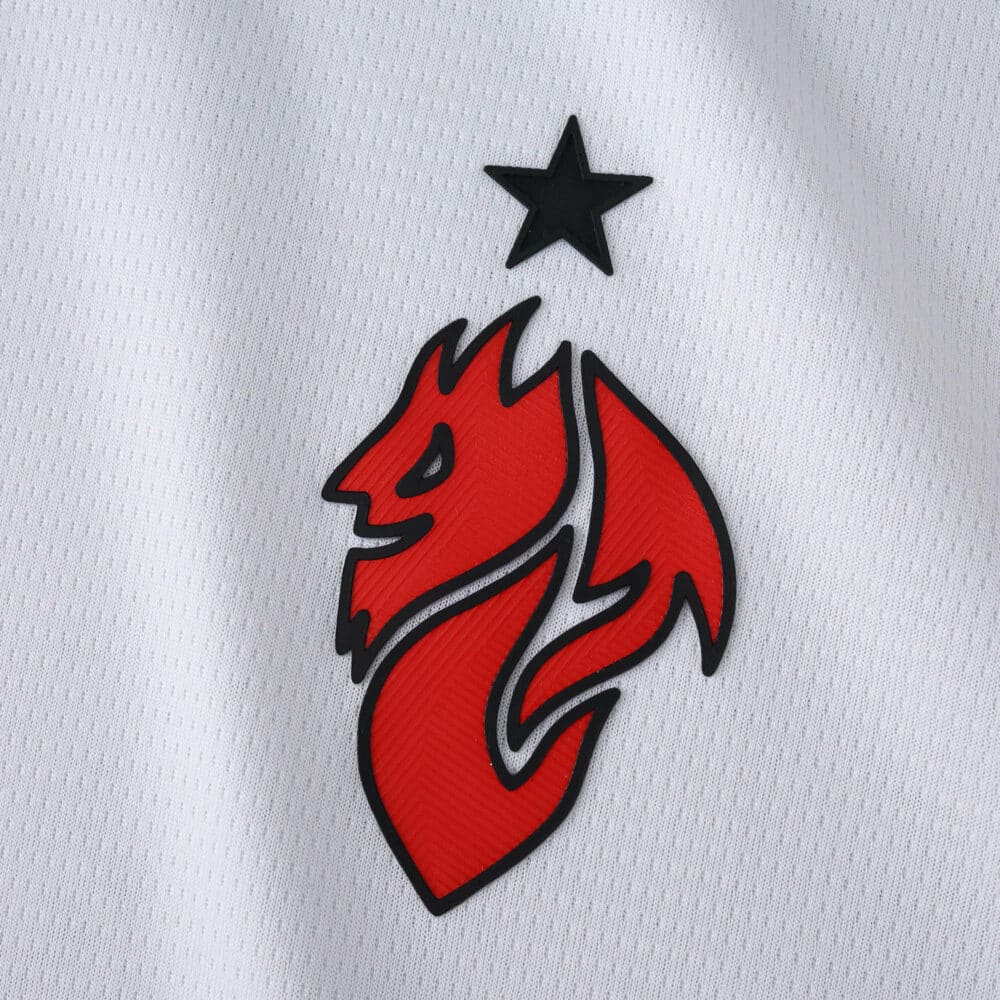 Close-up of the red AC Milan 2025/26 Away Fan Version badge with a black star on white fabric.
