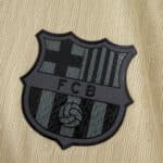 Close-up of the black Barcelona crest on the 2025/26 away player version jersey in gold fabric.
