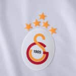 Galatasaray 2025/26 away fan jersey badge with five stars and "1905" on a white fabric background.