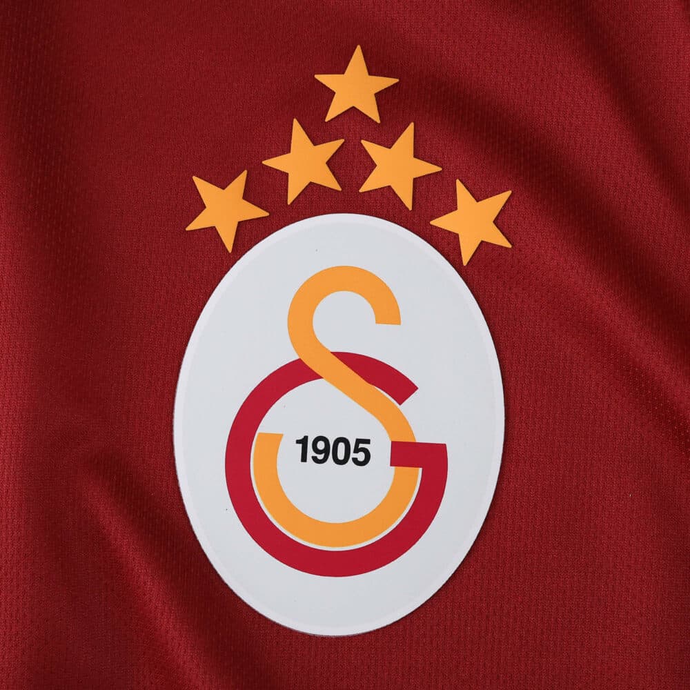 Close-up of the Galatasaray S.K. crest on the 2025/26 home fan version jersey, featuring five gold stars.