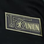 Close-up of the Union Berlin club crest on the 2025/26 away fan version jersey.
