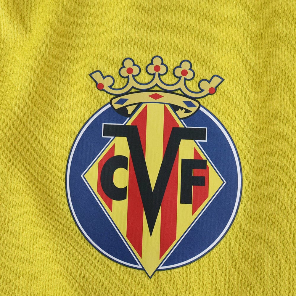 Villarreal CF crest on yellow fabric of the 2025/26 home fan jersey.