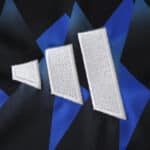 Close-up of the Hamburger SV 2025/26 home fan jersey showing the embroidered Adidas logo on a blue geometric pattern.