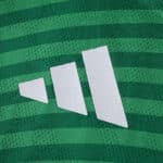 Close-up of Newcastle United 2025/26 away player version jersey with green stripes and white logo.