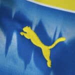 Close-up of the yellow Puma logo on the 2025/26 Parma Away Fan Version jersey with blue and yellow colors.
