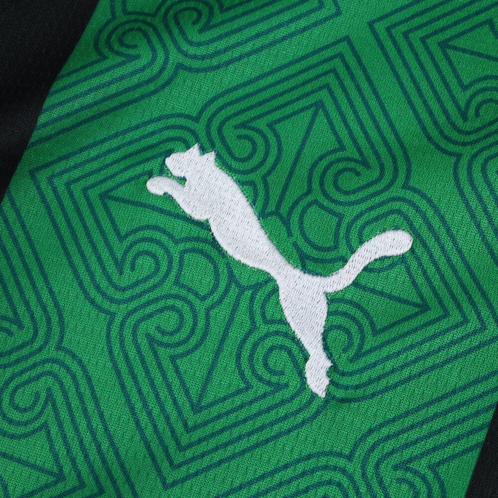 Close-up of the RC Lens 2025/26 away fan jersey fabric with green pattern and white Puma logo.