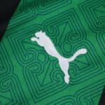 Close-up of the RC Lens 2025/26 away fan jersey fabric with green pattern and white Puma logo.