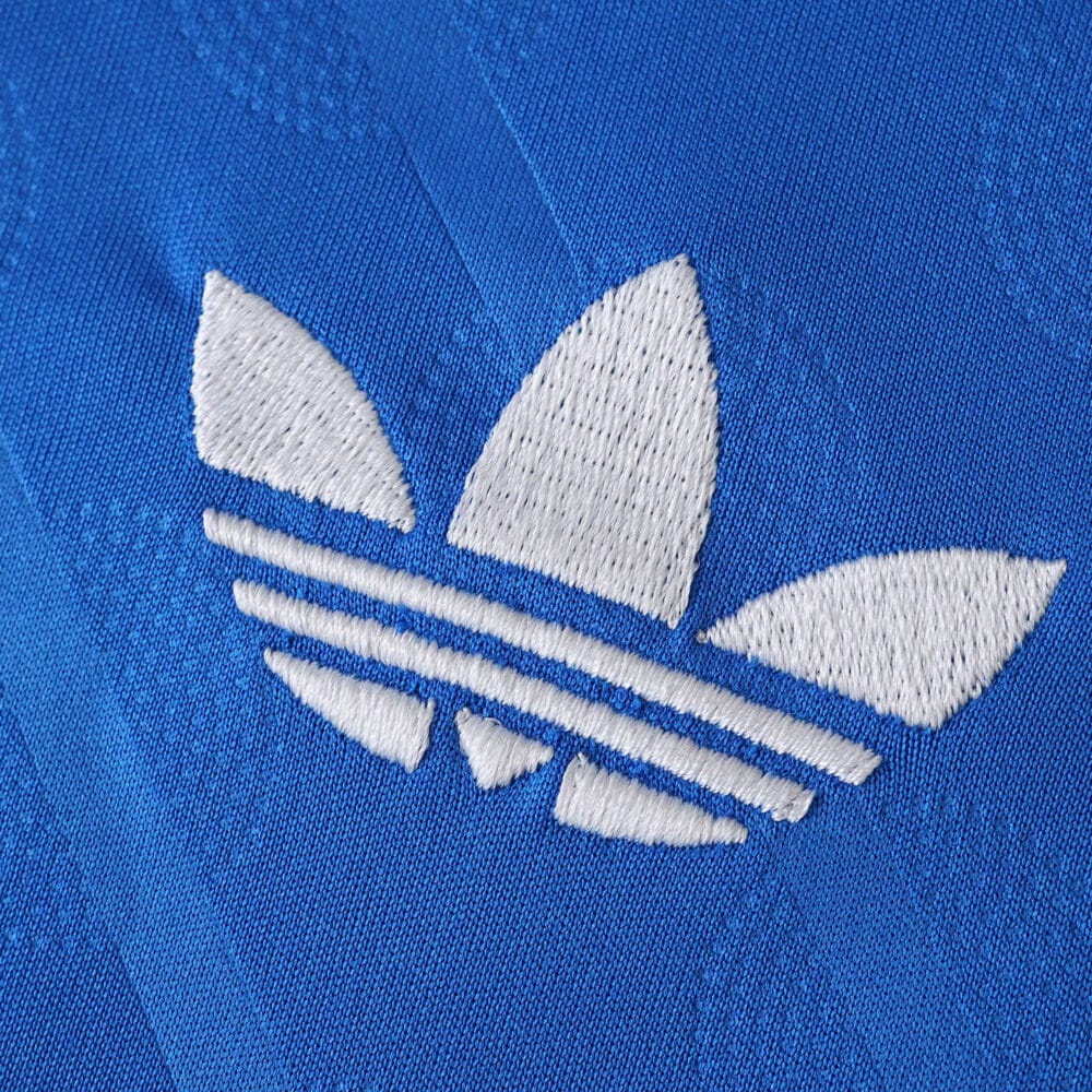 Close-up of the white Adidas Trefoil logo embroidered on the blue Real Madrid Third 2025/26 Fan Version jersey.