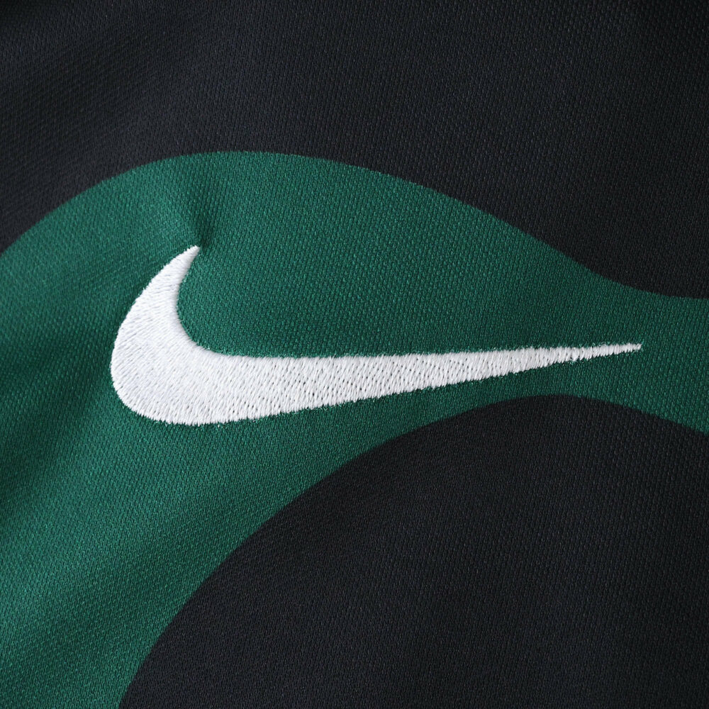 Close-up of Nike logo on the Sporting CP Third 2025/26 Fan Version jersey, green and black fabric visible.