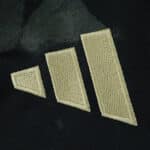 Close-up of the gold Adidas logo on the Union Berlin Away 2025/26 Fan Version jersey.