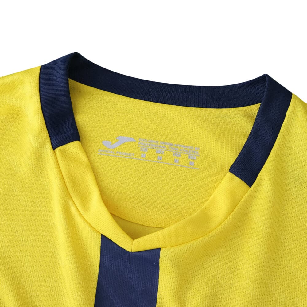 Close-up of the Villarreal 2025/26 home fan jersey collar in yellow with a navy blue V-neck design.